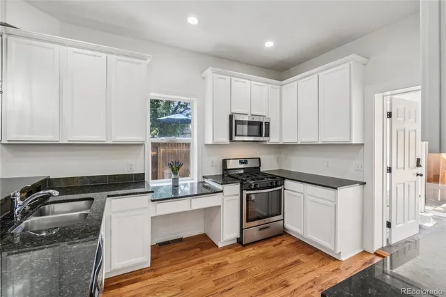 a kitchen with granite countertop white cabinets sink and stainless steel appliances