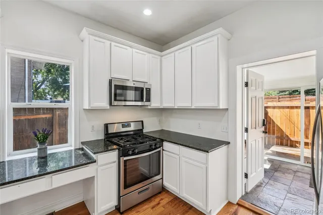 a kitchen with granite countertop white cabinets and black stainless steel appliances