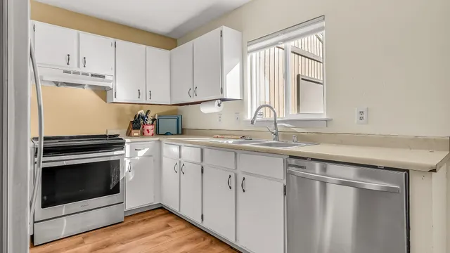 a kitchen with granite countertop white cabinets white stainless steel appliances and sink