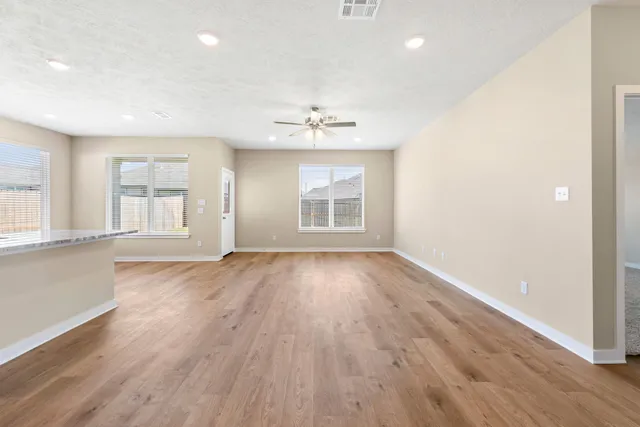 an empty room with wooden floor chandelier and windows
