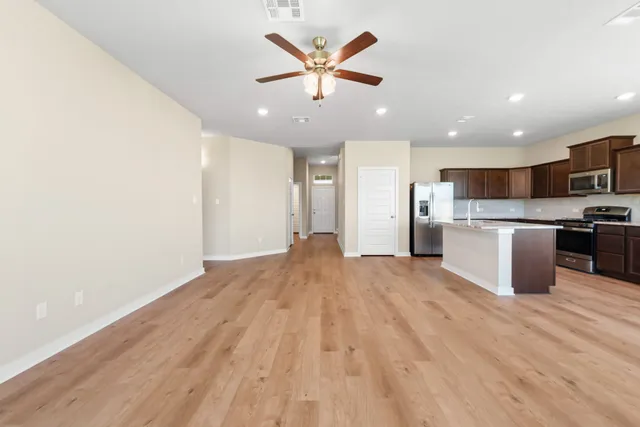 a view of kitchen with stainless steel appliances granite countertop a refrigerator and a stove top oven