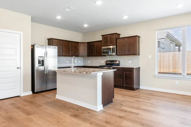 a kitchen with stainless steel appliances granite countertop a refrigerator and a stove top oven