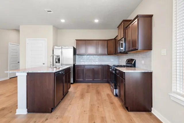 a kitchen with stainless steel appliances granite countertop a stove a sink and a microwave