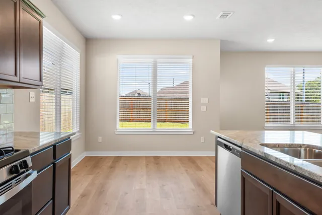 a kitchen with granite countertop a sink stove and cabinets