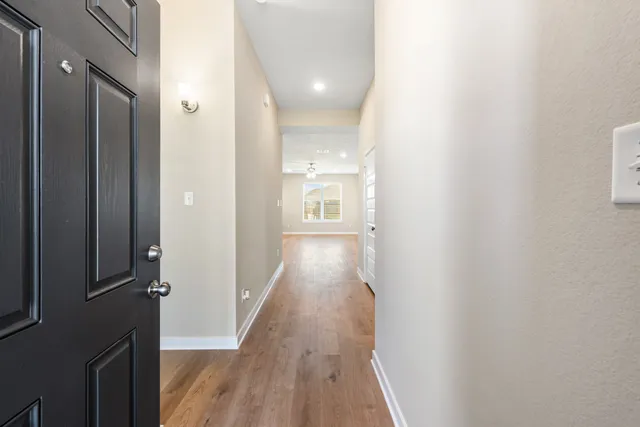 a view of a hallway with wooden floor and a bathroom