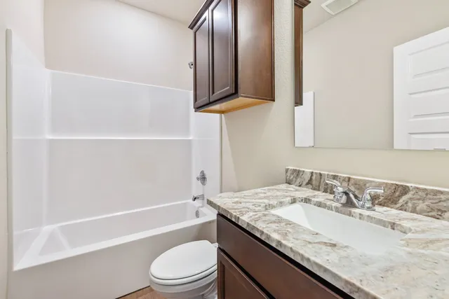 a bathroom with a granite countertop sink a toilet and bathtub