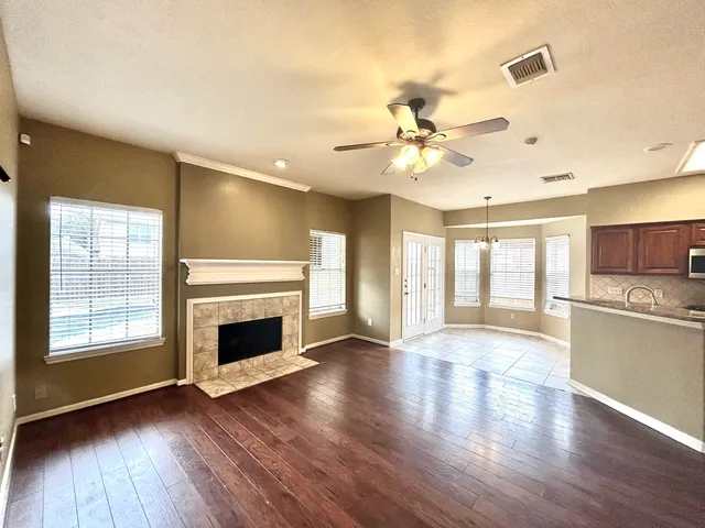 an empty room with wooden floor fireplace and windows
