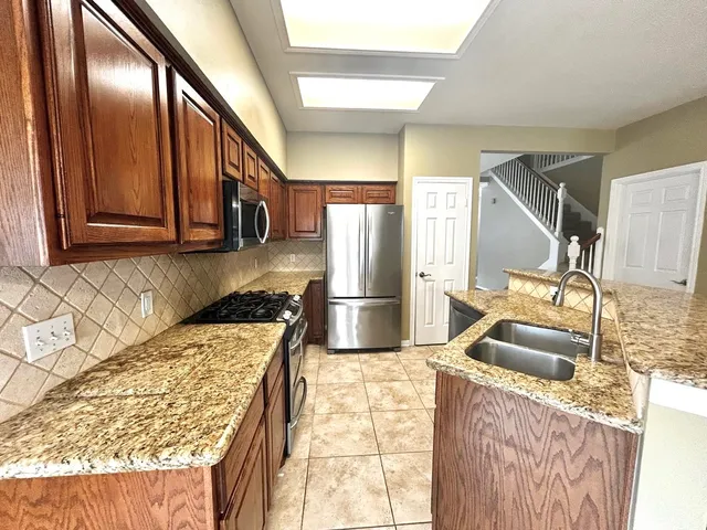 a kitchen with granite countertop stainless steel appliances a sink and cabinets