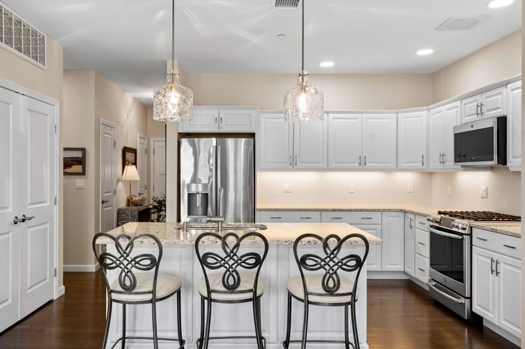 1 Revolution Way, Unit 201 Canton, MA 02021 - Photo 6 of 38 a kitchen with stainless steel appliances granite countertop a stove a sink a dining table and chairs with wooden floor