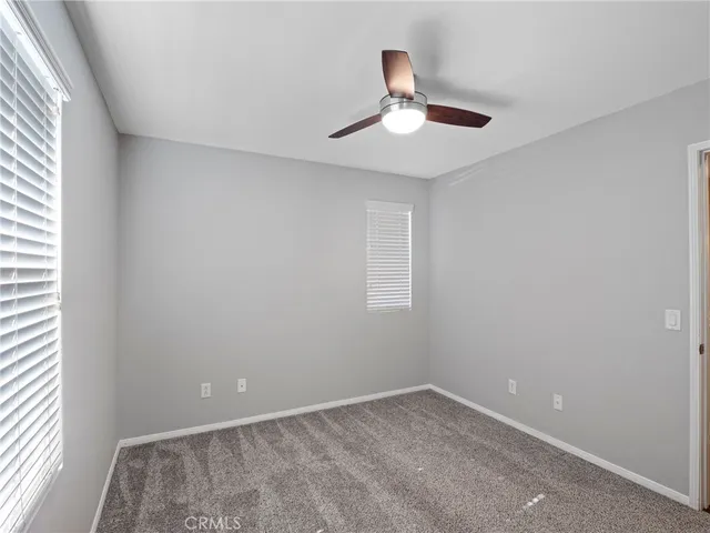 an empty room with a window and a fan