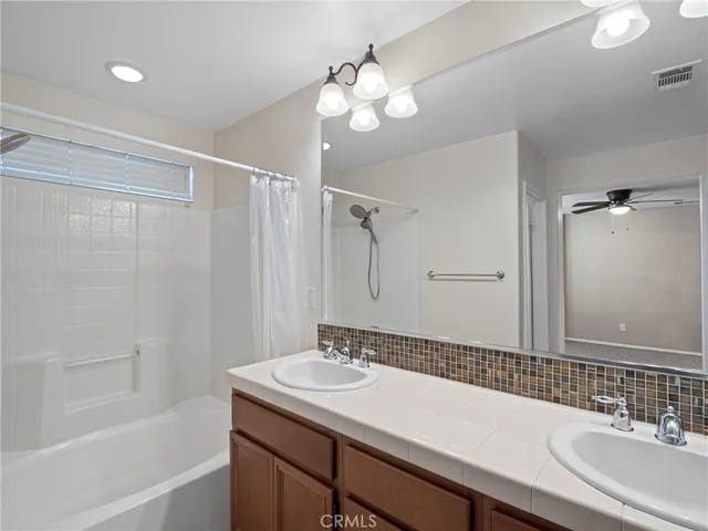 a bathroom with a sink double vanity granite tub shower and a mirror