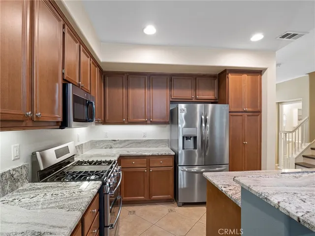 a kitchen with granite countertop wooden cabinets and stainless steel appliances