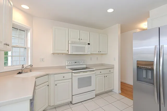 a kitchen with white cabinets and white appliances