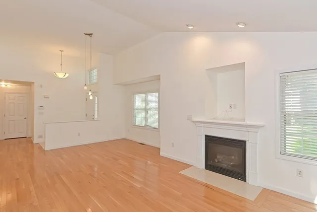 a view of empty room with a fireplace and wooden floor