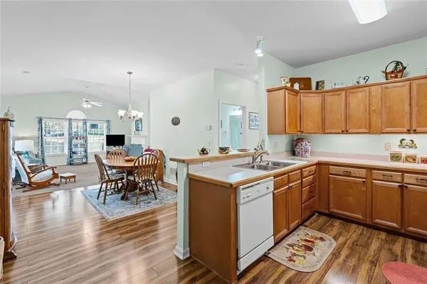 a kitchen with a sink stove and white cabinets with wooden floor