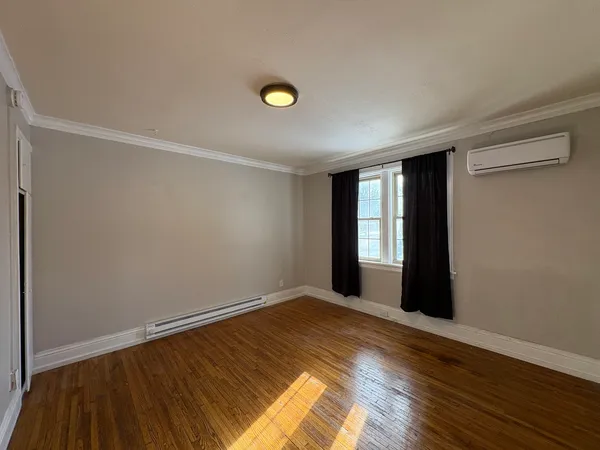 a view of empty room with wooden floor and fan