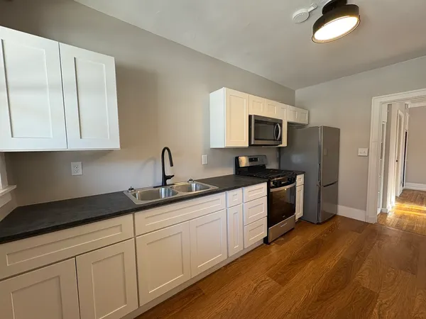 a kitchen with granite countertop white cabinets and stainless steel appliances