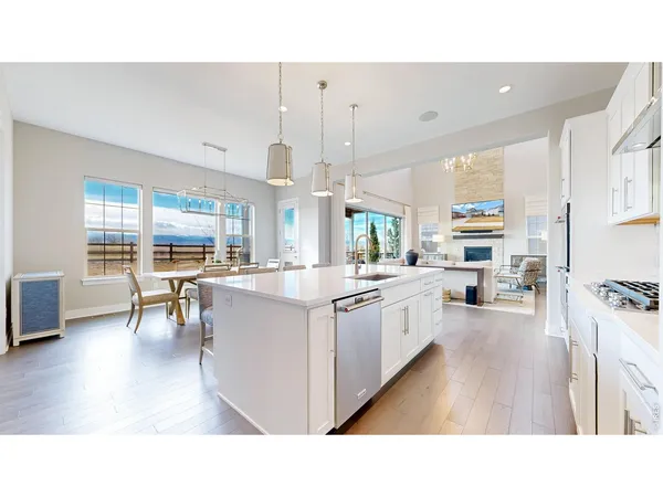 a living room with stainless steel appliances kitchen island granite countertop a large kitchen island a stove a sink a dining table and chairs with wooden floor
