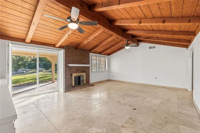 an empty room with ceiling fan and windows