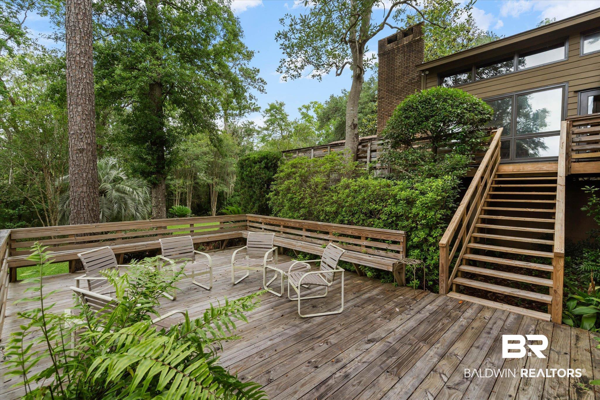 3500 Venetia Road Mobile, AL 36605 - Photo 28 of 56 Expansive wood-finish deck with built-in bench seating, surrounded by mature trees and lush landscaping