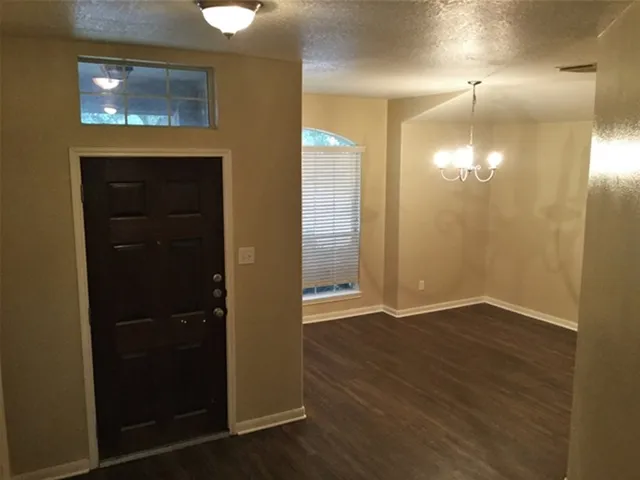 an empty room with wooden floor closet and windows