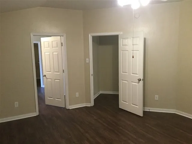 an empty room with wooden floor & closet area