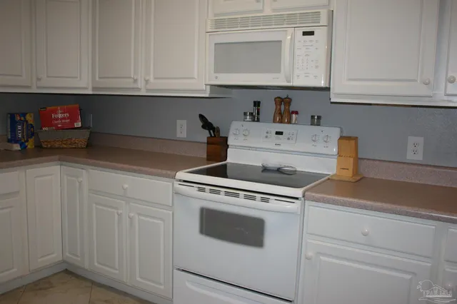 a kitchen with white cabinets and refrigerator