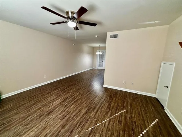 an empty room with wooden floor and a ceiling fan