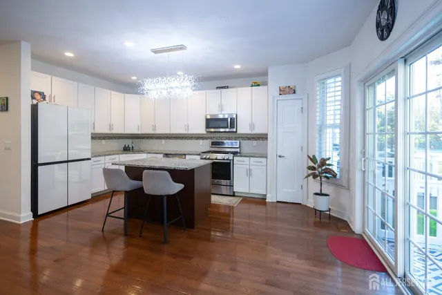 a kitchen with stainless steel appliances granite countertop a stove top oven a sink dishwasher a dining table and chairs with wooden floor