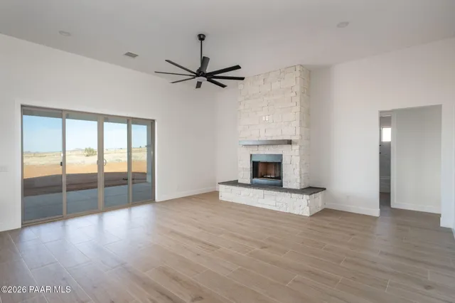 a view of an empty room with wooden floor and a fireplace