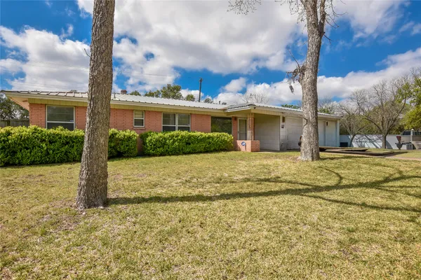 a view of a house with a yard and potted plants