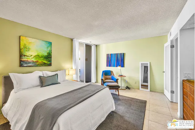 a bedroom with a bed a couch and painting on the wall