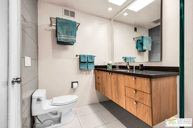 a bathroom with a granite countertop sink a toilet a mirror and shower