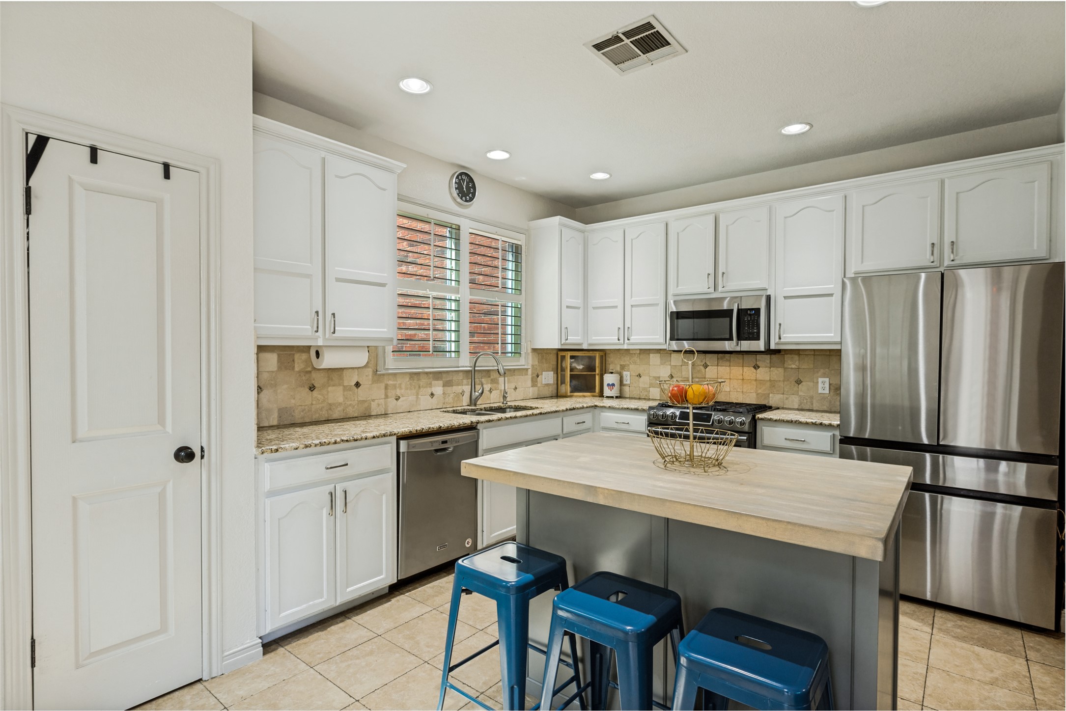 3803 Caney Creek Road Austin, TX 78732 - Photo 5 of 21 Ample cabinetry and tile floors enhance this functional culinary space with its central workspace.