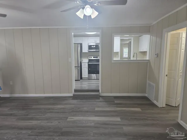 a view of a livingroom with wooden floor and a kitchen space