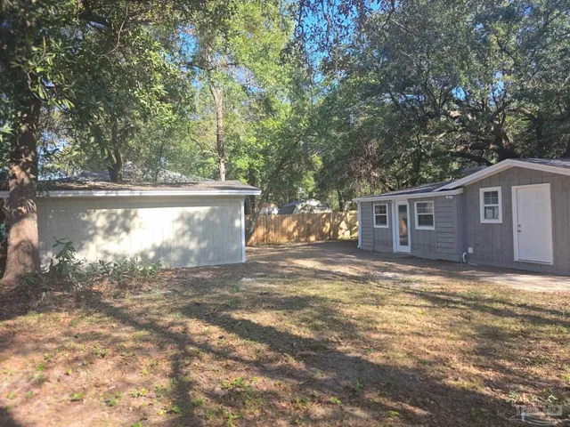 a view of a yard in front of a house with large trees