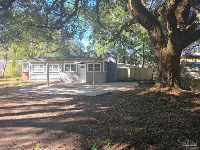 a view of house with backyard and a trees