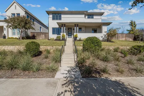 a view of a white house with a yard and potted plants