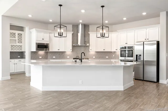 a large kitchen with granite countertop a large counter top a sink stainless steel appliances and cabinets