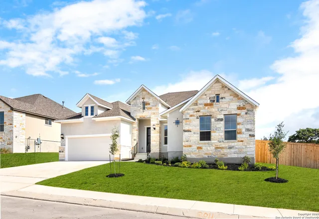 a view of a white house next to a yard with big trees