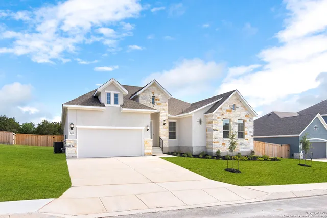 a view of a white house next to a yard with big trees