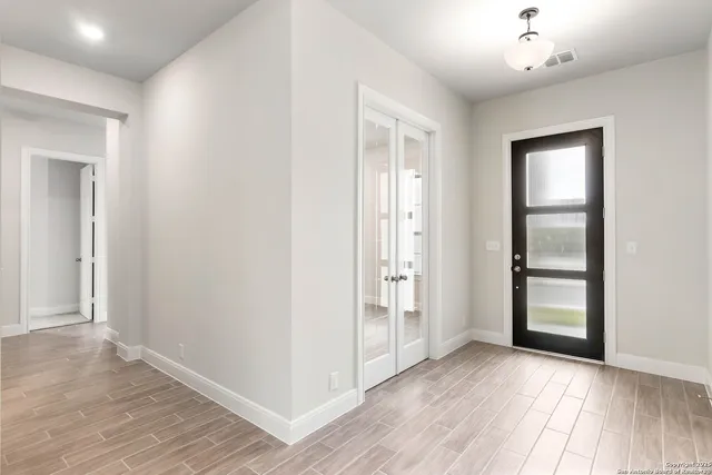 an empty room with wooden floor closet and windows