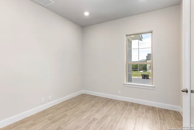 an empty room with wooden floor and windows