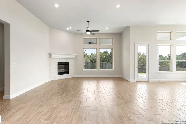 an empty room with wooden floor fireplace and windows
