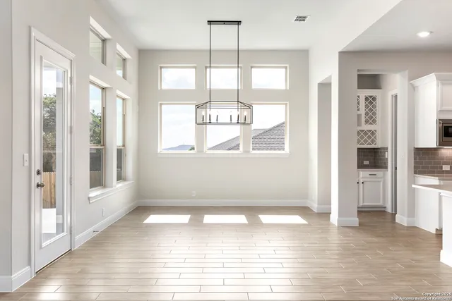 a view of an empty room with kitchen and window
