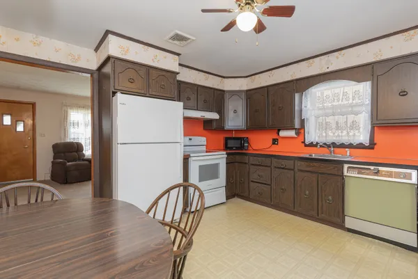 a kitchen with stainless steel appliances granite countertop a refrigerator a stove a sink a dining table and chairs with wooden floor