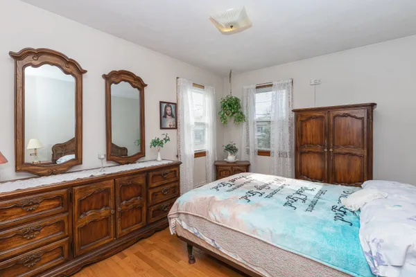 a bedroom with a large bed and dresser with mirror