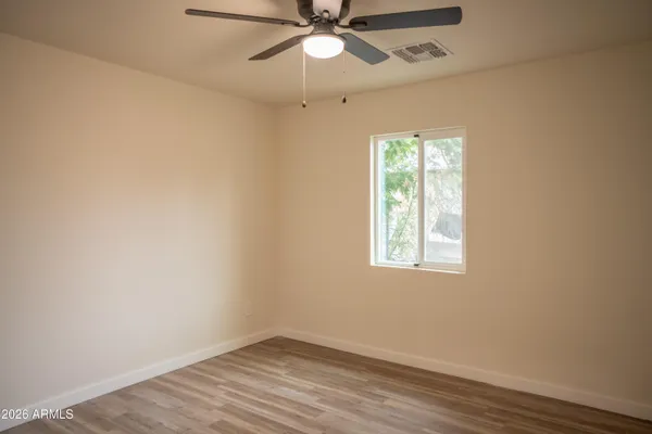 an empty room with wooden floor fan and windows