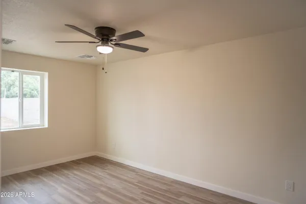 an empty room with wooden floor fan and windows