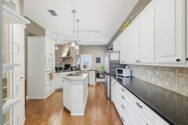 a large kitchen with stainless steel appliances granite countertop a lot of counter space and wooden floor